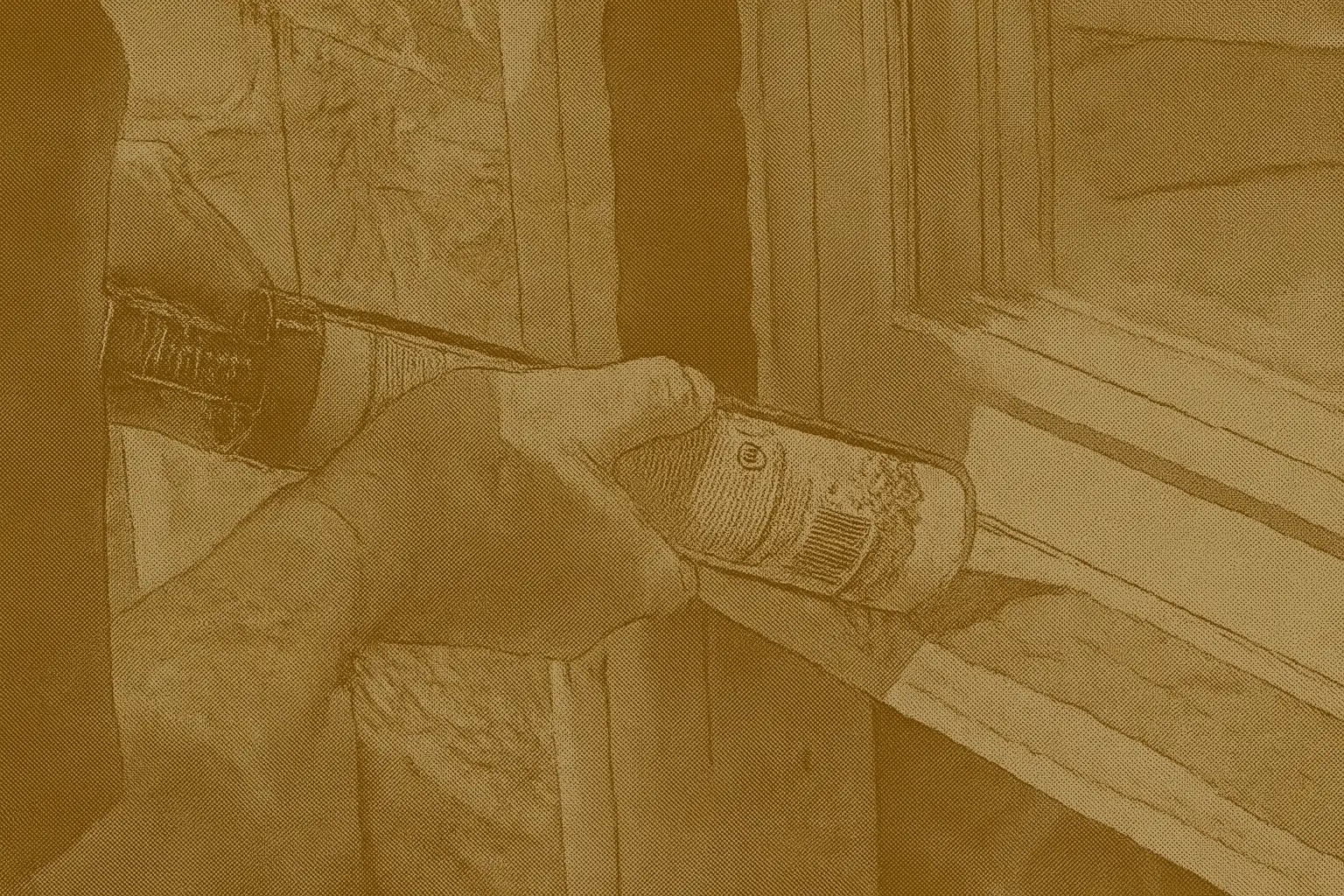 Close-up of hands applying caulk around a window frame to seal air leaks, illustrating an affordable weatherproofing step for winter energy savings.